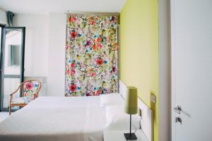 - une chambre avec un lit blanc et un rideau floral dans l'établissement Hotel Elite, à Salsomaggiore Terme