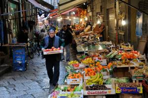 een man die door een markt loopt met dozen groenten en fruit bij Trilocale al Politeama - Zyz in Palermo