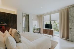a white bedroom with a large bed and a television at Casamaya Villa in Legian
