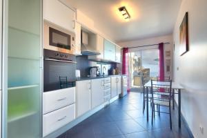 a kitchen with white cabinets and a table and chairs at Villa Araujo Da Costa by HR Madeira in Garajau