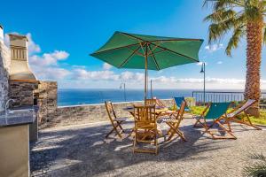 una mesa y sillas con sombrilla y el océano en Villa Araujo Da Costa by HR Madeira, en Garajau