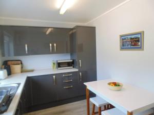a kitchen with black cabinets and a white counter top at Da Milk Shop Holiday Home in Scalloway