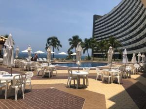 un grupo de mesas y sillas con sombrillas junto a una piscina en Ondina Apart Hotel 621, en Salvador