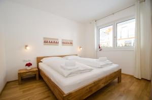 sypialnia z łóżkiem z białą pościelą i oknem w obiekcie Finest Kitzblick Golf Suites by All in One Apartments w mieście Zell am See