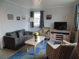 a living room with two couches and a tv at Da Milk Shop Holiday Home in Scalloway