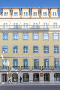 里斯本的住宿－Hotel MeraPrime Gold Lisboa，一座黄色的大建筑,前面的人在步行