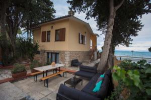 a house with couches and a table in front of it at Beach Front Villa-Families & Pet Friendly in Porto Santo Stefano