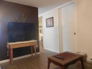 a living room with a desk and a television at Gite La Ptite Falaise hébergement touristique in Sainte-Anne-des-Monts +34 photos