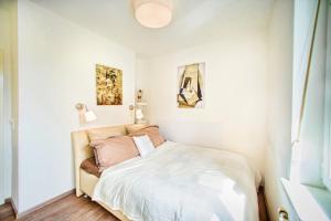 1 dormitorio con 1 cama con sábanas blancas y pinturas en Roof-Terrace Suite Gustav Mahler en Viena