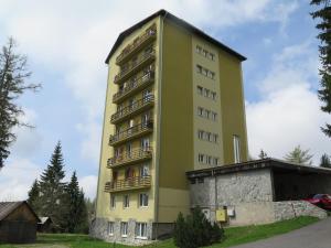 um edifício amarelo alto com varandas em Apartmán Tuček em Štrbské Pleso