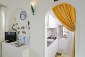 a kitchen with white cabinets and a tv on the wall at That's Atrani in Atrani