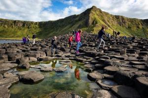 Eine Gruppe von Menschen, die über Felsen in einem Wasserbecken laufen in der Unterkunft Riverbank Apartment in Derry Londonderry