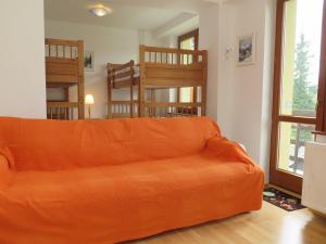 um sofá laranja sentado numa sala de estar com uma janela em Apartmán Tuček em Štrbské Pleso