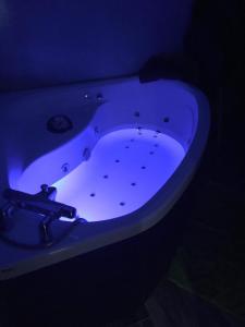bañera blanca en una habitación oscura en Chambre ZEN en Panazol