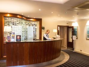 a woman standing at a bar in a hotel lobby at Harbour Heights Hotel in Poole