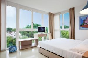 una camera con letto, TV e finestre di Art&Park Hotel Union Lido a Cavallino-Treporti