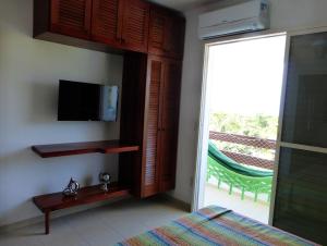 a bedroom with a tv and a bed and a sliding glass door at Condominio Wembley Forest Sea in Ubatuba