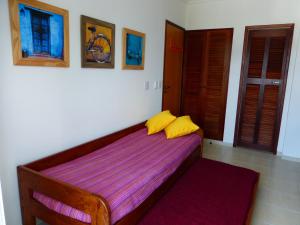 a bedroom with a bed with two yellow pillows on it at Condominio Wembley Forest Sea in Ubatuba