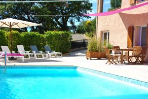 a swimming pool with chairs and a table and an umbrella at La Rabasse de Gallinette in Aups