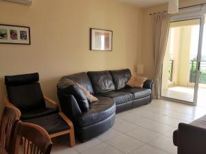 a living room with a leather couch and two chairs at Mazotos Panoramic Village in Mazotos