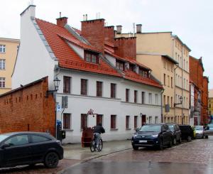eine Person, die vor einem weißen Gebäude Fahrrad fährt in der Unterkunft Apartament Carolina II in Toruń
