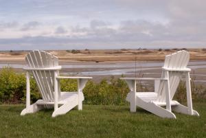 two white chairs and a table in the grass at The Dunes on the Waterfront in Ogunquit