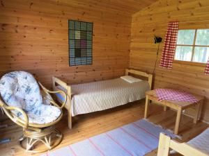 a bedroom in a log cabin with a bed and a chair at Vanha-Pälsilä lakeside farm in Kuhmoinen