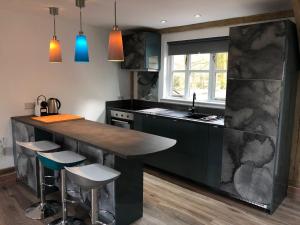 a kitchen with a large counter with stools around it at Finlaystone Family Barn in Port Glasgow