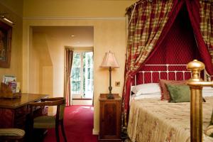 a bedroom with a bed with a red canopy at Ravenwood Hall Hotel in Bury Saint Edmunds