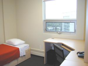 um quarto com uma cama, uma secretária e uma janela em University of Alberta - Accommodation em Edmonton