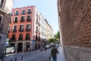 a man walking down a street next to buildings at Apartamentos Day Madrid BALLESTA Centro Gran Via Sol Malasaña in Madrid