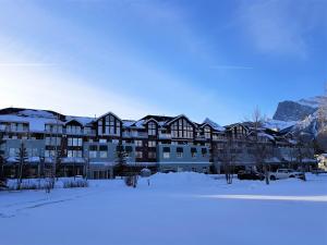 a large building in the snow with a parking lot at Sunset Mountain Inn in Canmore