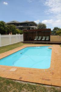 a large blue swimming pool in a yard at Horizon Cottages in Noordhoek