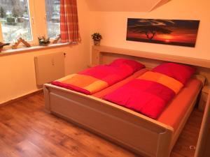 ein Bett mit zwei roten und gelben Kissen darauf in der Unterkunft Pöhlbergblick Annaberg in Annaberg-Buchholz