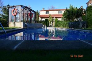 una piscina di fronte a un edificio con un cartello di Casa Rural Os Carballos a Pontevedra
