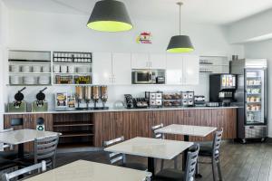 a restaurant with tables and chairs and a kitchen at Super 8 by Wyndham Winnipeg West in Winnipeg