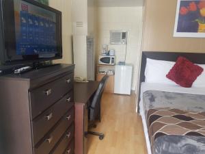 a bedroom with a bed and a desk with a television at West Castle Motel in Pincher Creek