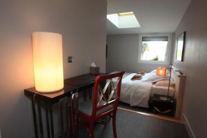 a bedroom with a bed and a desk with a lamp at LOGIS Hotel-Restaurant Le Relais d'Aligre in Châteauneuf-en-Thymerais