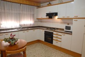 a kitchen with white cabinets and a table with a vase of flowers at Ca la Viola in Marçà