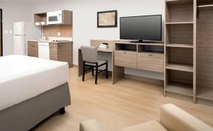 a bedroom with a bed and a desk with a television at WoodSpring Suites Seattle Redmond in Redmond