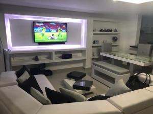 a living room with a tv and white furniture at Sashii Hostel & Boutique. in Ríohacha