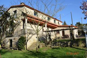 una gran casa de piedra con un patio de césped en Casa Rural Os Carballos en Pontevedra