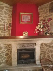 a fireplace in a room with a red wall at Casa Rural Os Carballos in Pontevedra