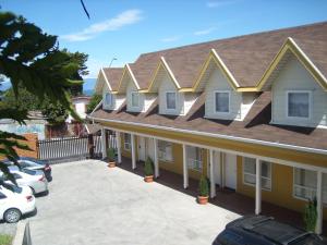 Apart Hotel en Puerto Montt في بويرتو مونت: منزل اصفر مع سقف مع موقف سيارة