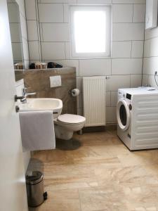 a bathroom with a toilet sink and a washing machine at Hugo18 Boardinghouse in Kandel