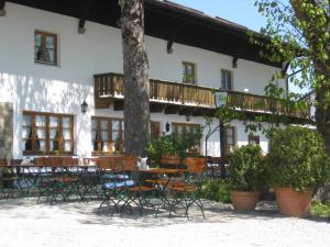 ein Gebäude mit Tischen, Stühlen und einem Baum in der Unterkunft Hotel Haflhof in Egmating