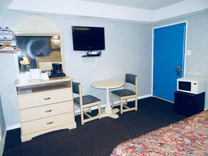 um quarto de hotel com uma cama e uma secretária com uma mesa e uma televisão em Village Inn & Suites - Smithville em Smithville