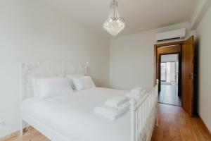 a white bedroom with a white bed and a chandelier at Casa da Avenida in Olhão