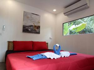 a bedroom with a red bed with two towels on it at Ozone Beach Huts in Ko Lanta
