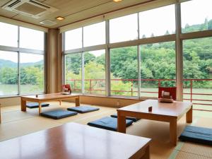 Habitación grande con mesas y ventanas grandes. en momijigawa onsen, en Naka